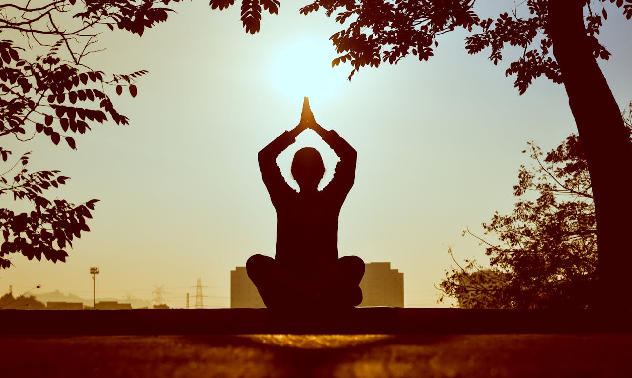 services-02 Silhouette of a person practicing yoga outdoors during sunrise, creating a calming atmosphere.